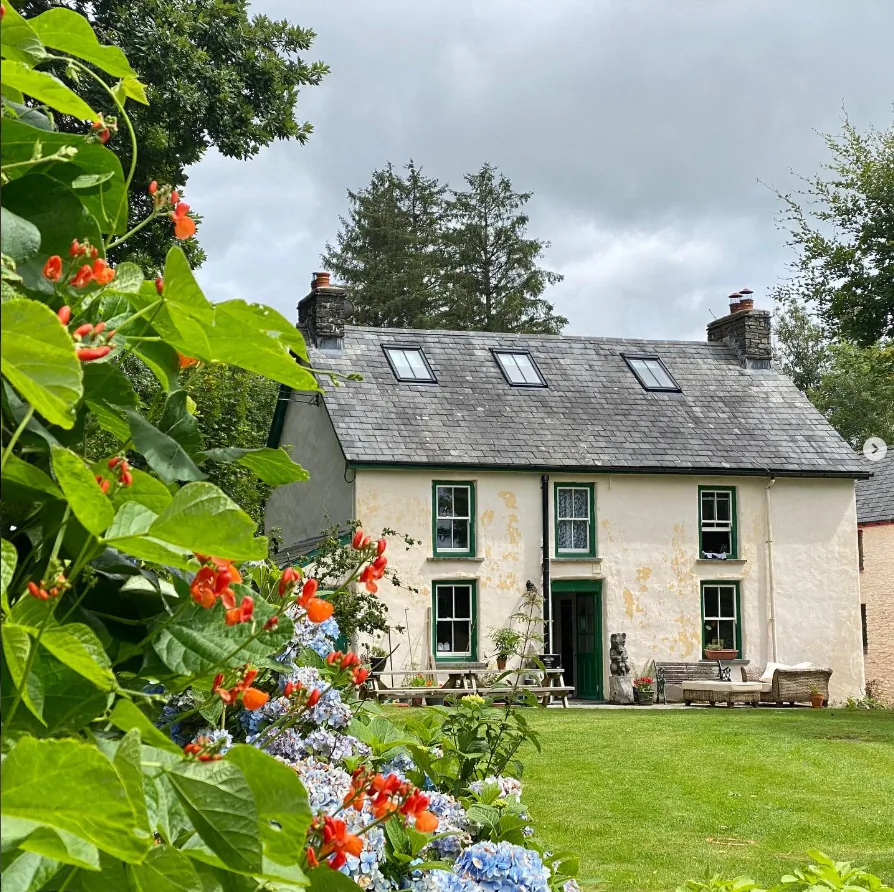 The Victorian Farmhouse in summer with orange flowers and hydrangeas